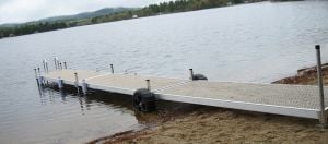  An aluminum rolling dock in the water, featuring two large rubber tires on either side where the water meets the shore.