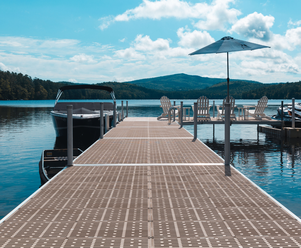 A dock with chairs and an umbrella overlooking a serene lake.