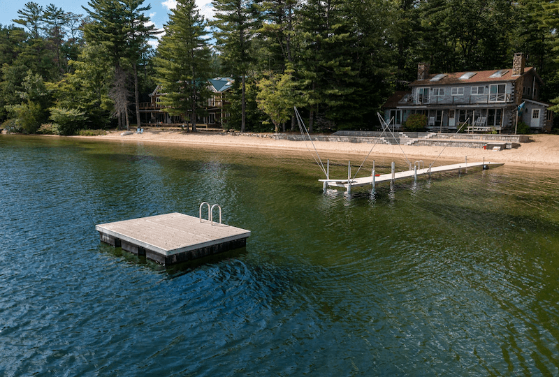 An-I-shaped-dock-with-mooring-lines-extends-onto-a-lake.-A-swim-platform-with-a-ladder-floats-further-out-from-the-dock.