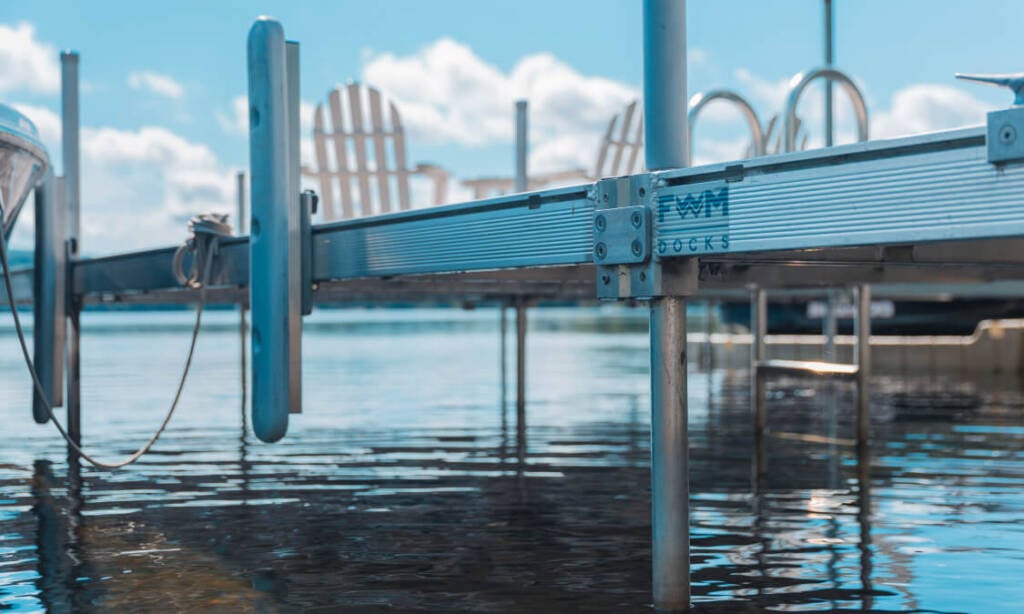 a close up photo of a metal dock in water, logo on dock says FWM Docks