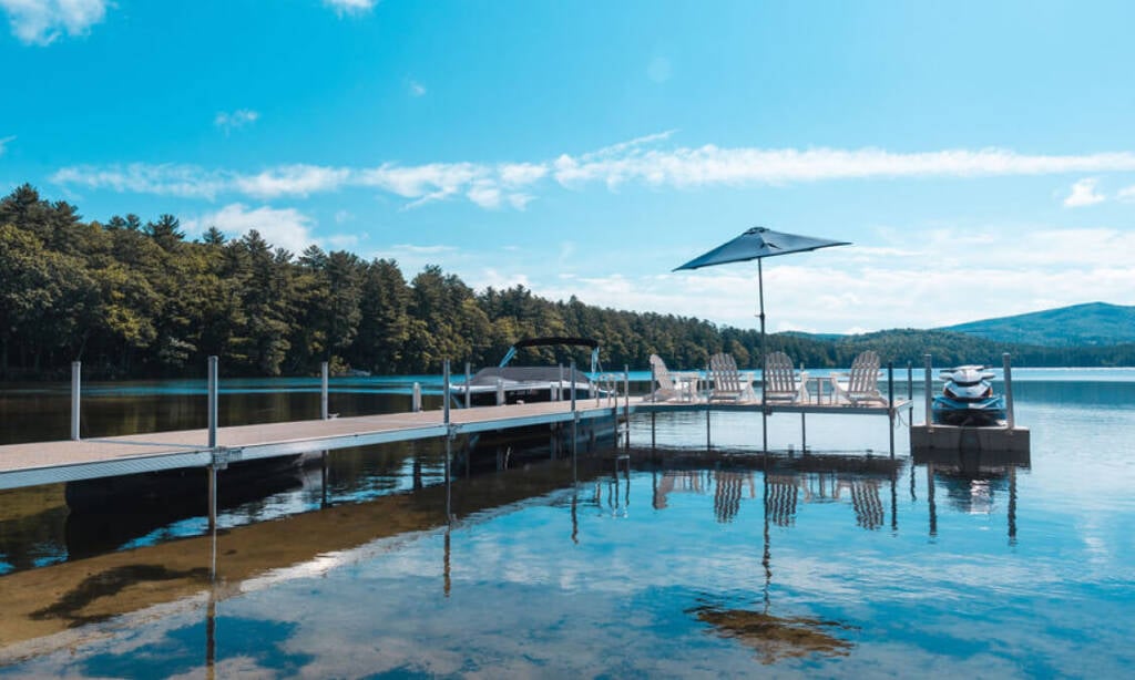 image of a dock on a lake, the doc has lounge chairs and a seadoo is parked by the dock