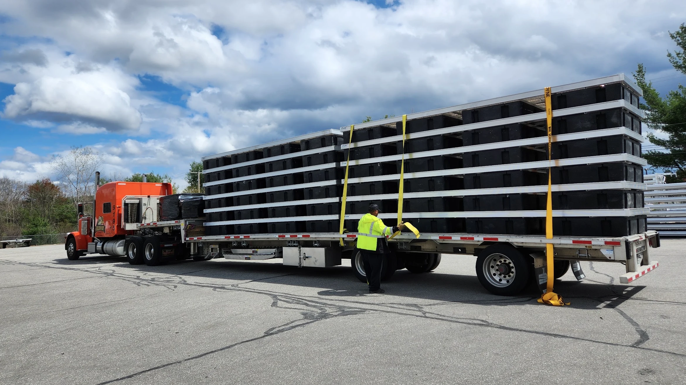 FWM aluminum floating dock sections stacked and secured on a flatbed truck for transport.